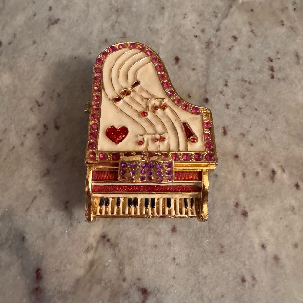 an elegant piano, cream, red crystals surrounded in gold trim trinket